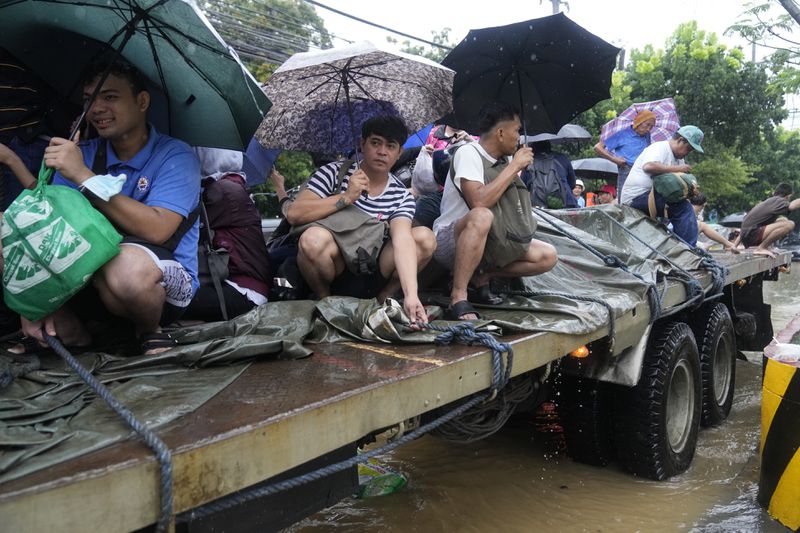 Residents ride a truck as they negotiate a flooded street caused by heavy rains from Tropical Storm Yagi, locally called Enteng, in Cainta, Rizal province, Philippines, Monday, Sept. 2, 2024. (AP Photo/Aaron Favila)