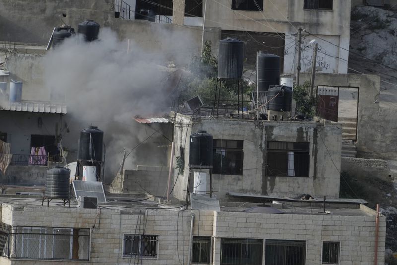 EDS NOTE: GRAPHIC CONTENT - An explosion is seen with three bodies lie motionless on rooftops in the West Bank town of Qatabiya during a raid, Thursday, Sept. 19, 2024. (AP Photo/Majdi Mohammed)