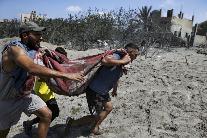 Palestinians evacuate a dead person from a site hit by an Israeli bombardment on Khan Younis, southern Gaza Strip, Saturday, July 13, 2024. Israel said it targeted Hamas’ shadowy military commander in a massive strike Saturday in the crowded southern Gaza Strip that killed at least 71 people, according to local health officials. Hamas immediately rejected the claim that Mohammed Deif was in the area. (AP Photo/Jehad Alshrafi)