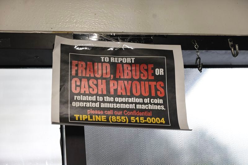 A sign with a tip line phone number for lottery slot machine fraud hangs inside of a gas station in Atlanta. (Natrice Miller/natrice.miller@ajc.com)