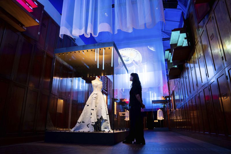 A member of staff views exhibits from previous concert tours that are displayed at the 'Taylor Swift Songbook Trail Exhibition' at the Victoria & Albert Museum, on Wednesday, July 24, 2024 in London. (Photo by Scott A Garfitt/Invision/AP)