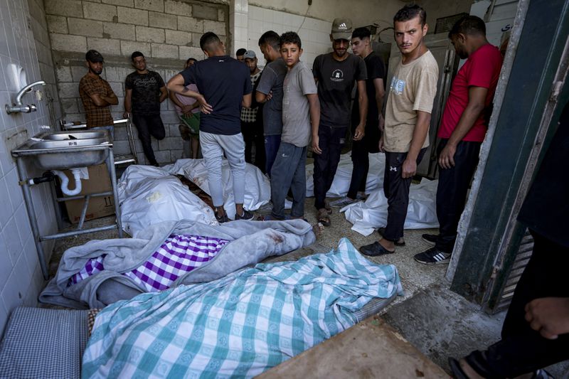 Palestinians check the bodies of their relatives killed in the Israeli bombardment of the Gaza Strip, at a hospital morgue in Deir al-Balah, Thursday, Aug. 22, 2024. (AP Photo/Abdel Kareem Hana)