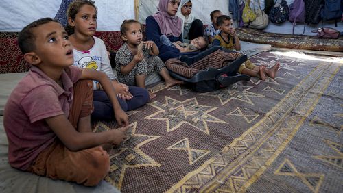 Displaced infant Abdel-Rahman Abuel-Jedian, 11-month-old, who suffers from polio, is carried by his mother, center, at a makeshift tent camp in Deir al-Balah, central Gaza Strip, Tuesday, Aug. 27, 2024. (AP Photo/Abdel Kareem Hana)