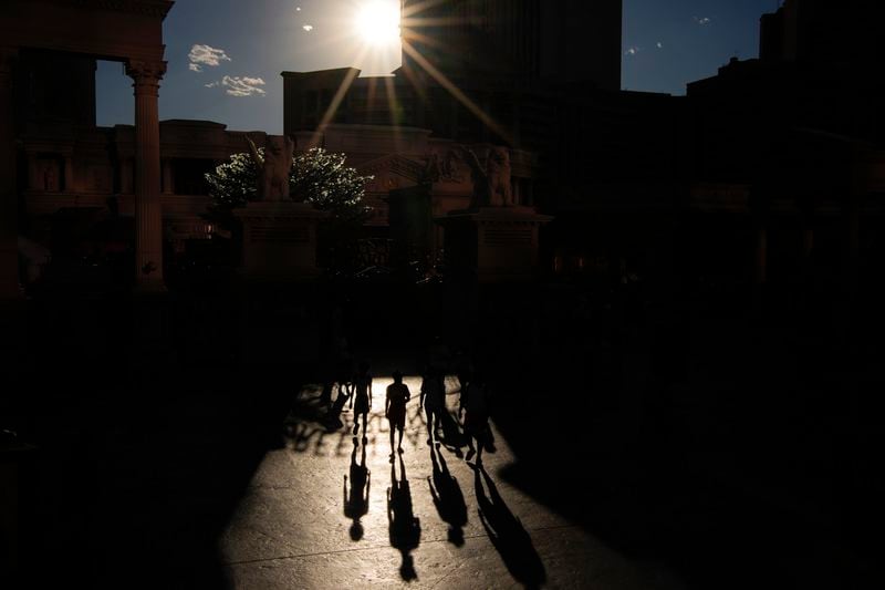 People walk in the sun along the Las Vegas Strip, Sunday, July 7, 2024, in Las Vegas. The city set an all time record high of 120 F (48.8 C) Sunday as a heat wave spread across the Western U.S. sending many residents in search of a cool haven from the dangerously high temperatures. (AP Photo/John Locher)
