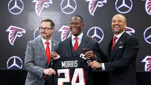 Atlanta Falcons new coach Raheem Morris poses with a Falcons jersey at Mercedes-Benz Stadium, Monday, February 5, 2024, in Atlanta. Also pictured is Falcons president Greg Beadles, left, and general manager Terry Fontenot. (Jason Getz / Jason.Getz@ajc.com)