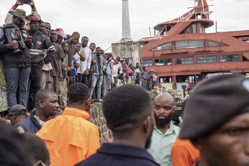 People gather at the port of Goma, Democratic Republic of Congo, after a ferry carrying hundreds capsized on arrival Thursday, Oct. 3, 2024, killing scores. (AP Photo/Moses Sawasawa)