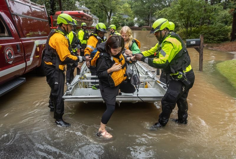 Atlanta Fire Rescue’s Dive/Swift Water Team came to the aid of Hyde Manor Drive residents Friday morning. Here, Maggie Blease and her daughter, Audrey, 12, were ferried to safety. Hurricane Helene brought heavy rain and high winds across Georgia. Helene, which entered Georgia as a Category 2 hurricane Friday morning, Sept. 27, 2024 downgraded to a tropical storm but brought a lot of problems to Atlanta with numerous water rescues and incessant rain. More than 1.1 million power outages have been reported statewide, and flash flooding remained a major concern. (John Spink/AJC)