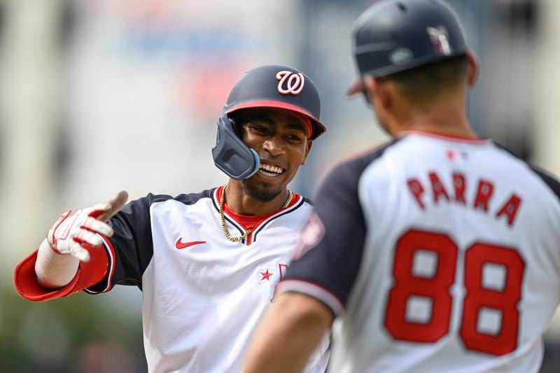 Washington Nationals' Darren Baker, left, is congratulated by first base coach Gerardo Parra after he got his first major league hit during the ninth inning of a baseball game against the Chicago Cubs, Sunday, Sept. 1, 2024, in Washington. (AP Photo/John McDonnell)