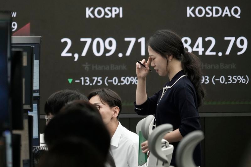 A currency trader reacts near the screen showing the Korea Composite Stock Price Index (KOSPI), left, at the foreign exchange dealing room of the KEB Hana Bank headquarters in Seoul, South Korea, Thursday, May 23, 2024. (AP Photo/Ahn Young-joon)