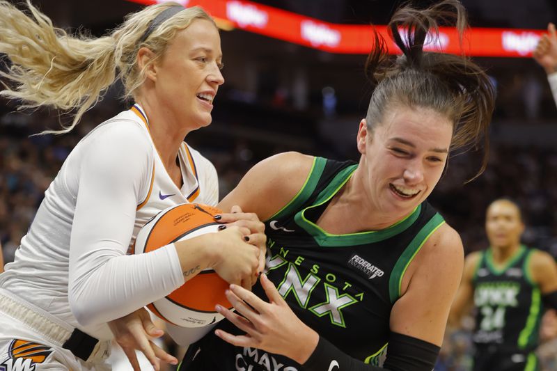 Phoenix Mercury guard Sophie Cunningham, left, forces a jump ball on Minnesota Lynx forward Bridget Carleton in the first quarter of Game 2 of a WNBA basketball first-round playoff game, Wednesday, Sept. 25, 2024, in Minneapolis. (AP Photo/Bruce Kluckhohn)