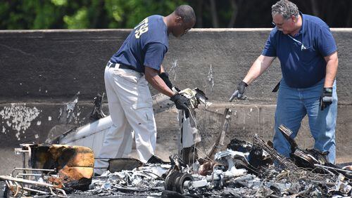 May 8, 2015 Atlanta - NTSB Safety Investigator Eric Alleyne (left) and other official investigate on I-285 at Peachtree Industrial Boulevard, where four people died aboard a small plan on Friday, May 8, 2015. Traffic was shut down in both directions. Three men and one woman were killed in the crash, according to Channel 2 Action News. The National Transportation Safety Board is in charge of the investigation and will determine probable cause. HYOSUB SHIN / HSHIN@AJC.COM