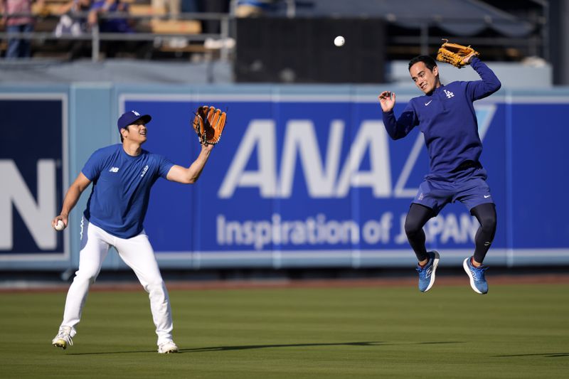 Los Angeles Dodgers interpreter Will Ireton, right, is unable to reach a batted ball while trying to protect Shohei Ohtani as Ohtani warms up prior to a baseball game against the San Diego Padres, Tuesday, Sept. 24, 2024, in Los Angeles. (AP Photo/Mark J. Terrill)