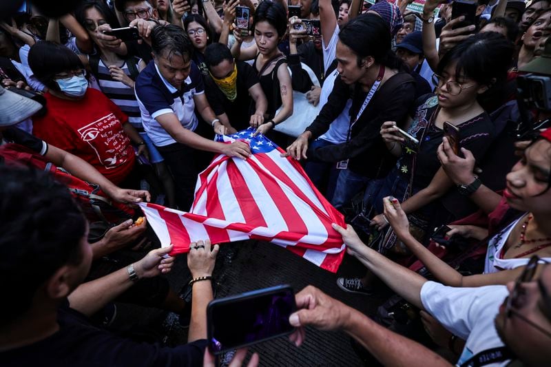 Activists tear a U.S. flag during a rally near the U.S. Embassy in Manila Saturday, Oct. 5, 2024, as they hold a protest to observe the first-year anniversary of the war in Gaza.(AP Photo/Gerard V. Carreon)