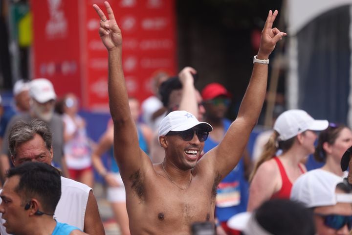 Runners celebrate at the finish of the 55th running of the Atlanta Journal-Constitution Peachtree Road Race in Atlanta on Thursday, July 4, 2024.   (Jason Getz / AJC)