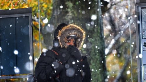 A lady covers her face at a Marta bus station as a wintry mix of sleet and snow is falling in East Atlanta Village. HYOSUB SHIN / HSHIN@AJC.COM