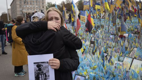 People react during a nationwide minute of silence in memory of fallen soldiers, who defended their homeland in war with Russia, on Defenders Day at the improvised war memorial in Independence square in Kyiv, Ukraine, Tuesday, Oct. 1, 2024. (AP Photo/Efrem Lukatsky)