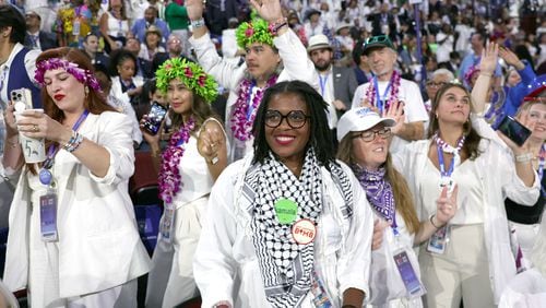 Delegates dressed in white hold their hands over their hearts during the pledge of allegiance at the start of the fourth day of the Democratic National Convention in Chicago on Thursday, Aug. 22, 2024. (Arvin Temkar/ AJC )