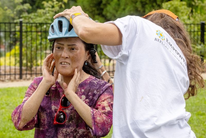  Program Manager Temple Moore helps Sediqa Nauruzi properly fit her bike helmet before Nauruzi's first bike riding lesson in Decatur Saturday. July 23, 2023. (Steve Schaefer/steve.schaefer@ajc.com)