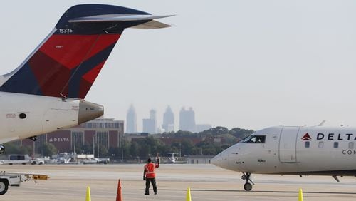 A Delta Air Lines ground crew member guides an aircraft on the tarmac on August 8, 2019, at Hartsfield-Jackson International Airport in Atlanta. (Bob Andres / robert.andres@ajc.com)