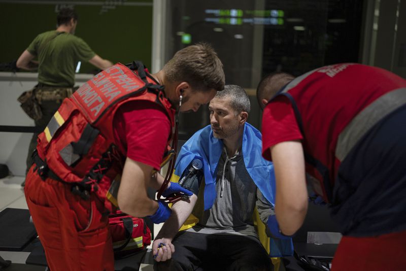Medics check the health of Ivan Levytskyi, who was recently released from Russian captivity, in Kyiv airport, Ukraine, Saturday, June 29, 2024. Ten Ukrainians who had been held prisoners for years, were released from Russian captivity on Friday with a mediation of Vatican, said Ukraine's President Volodymyr Zelenskyy. (AP Photo/Alex Babenko)