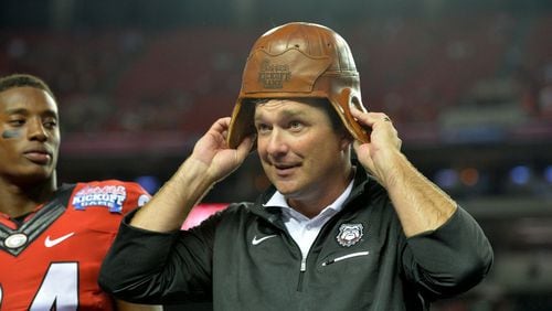 Kirby Smart tries on the Chick-fil-A Kickoff game’s Old Leather Helmet after his first team beat North Carolina at the Georgia Dome in 2016. (AJC file)