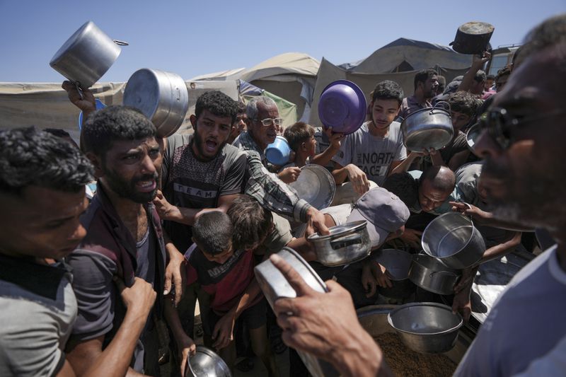 Displaced Palestinians gather at a food distribution center in Deir al Balah, central Gaza Strip, Friday, Aug. 23, 2024. (AP Photo/Abdel Kareem Hana)