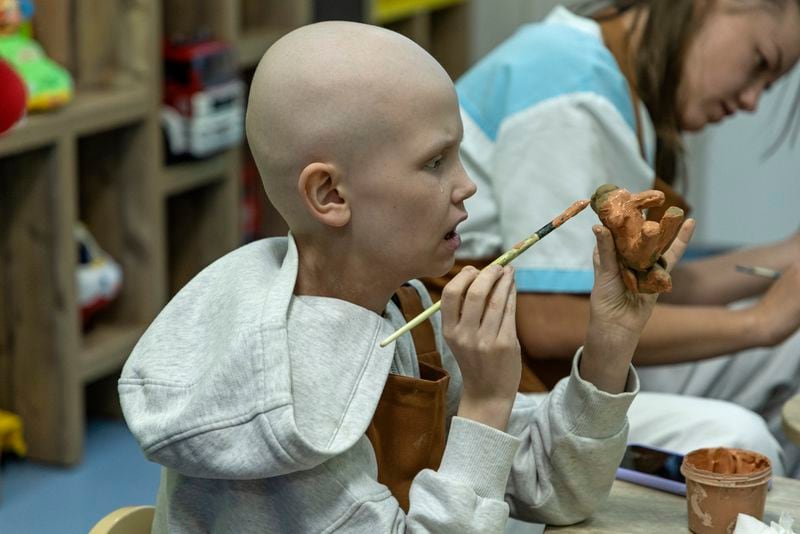 Kira Vertetska, 8, who is undergoing treatment in the oncology department at Okhmatdyt children's hospital in Kyiv, Ukraine, paints a clay figure, Thursday Sept. 19, 2024. (AP Photo/Anton Shtuka)