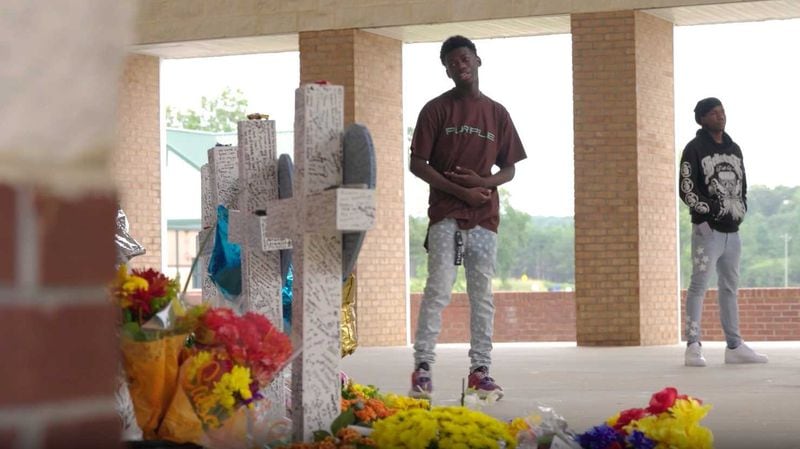 Apalachee High School student Isaac Sanguma looks at a memorial for the victims of the Sept. 4 shooting at his school. Sanguma wrote a rap song in tribute to the vicitms. (Tyson Horne/AJC)