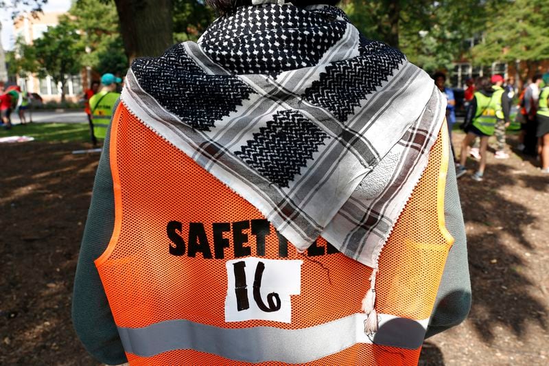 YM Masood stands in Union Park in Chicago on Monday, Aug. 19, 2024. The 20-year-old college student and activist, who is Muslim and of Indian descent, wears traditional Middle Eastern keffiyeh scarves which belonged to his father and late uncle. "I have this duty to carry on … what (my uncle) stood for and bring new meaning to it," he says. (AP Photo/Martha Irvine)