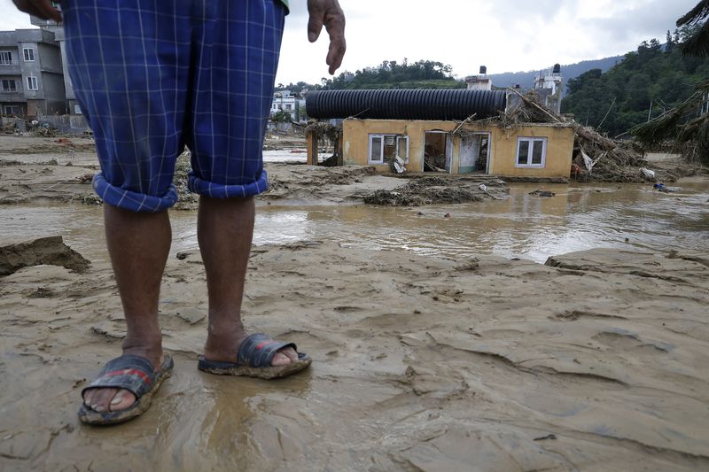 A man stands on a muddy plain next to a damaged structure in Kathmandu, Nepal, Monday, Sept. 30, 2024 in the aftermath of a flood caused by heavy rains . (AP Photo/Gopen Rai)