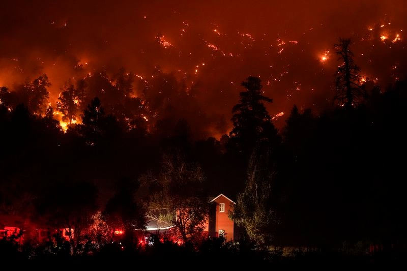 Firetrucks are seen around a building as scorched trees smolder during the Bridge Fire in Wrightwood, Calif., Wednesday, Sept. 11, 2024. (AP Photo/Jae C. Hong)