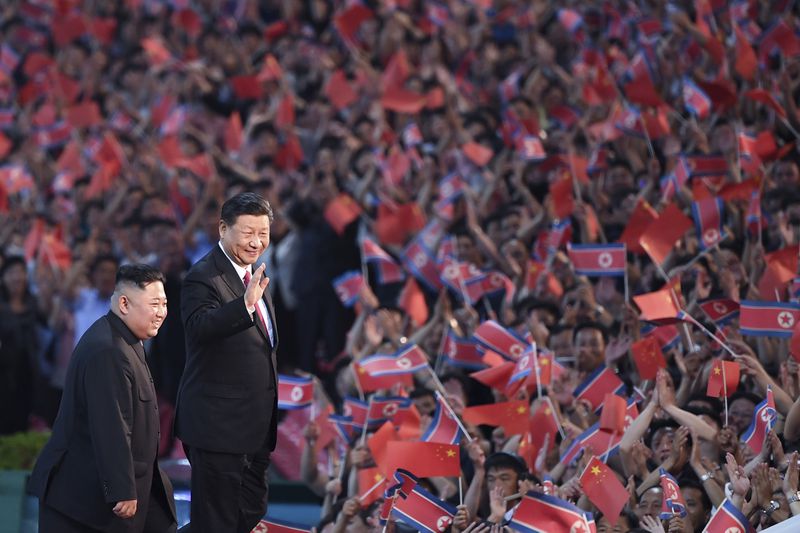 FILE - In this photo released by China's Xinhua News Agency, spectators wave Chinese and North Korean flags as North Korean leader Kim Jong Un, left, and visiting Chinese President Xi Jinping attend a mass gymnastic performance at the May Day Stadium in Pyongyang, North Korea, on June 20, 2019. (Yan Yan/Xinhua via AP, File)