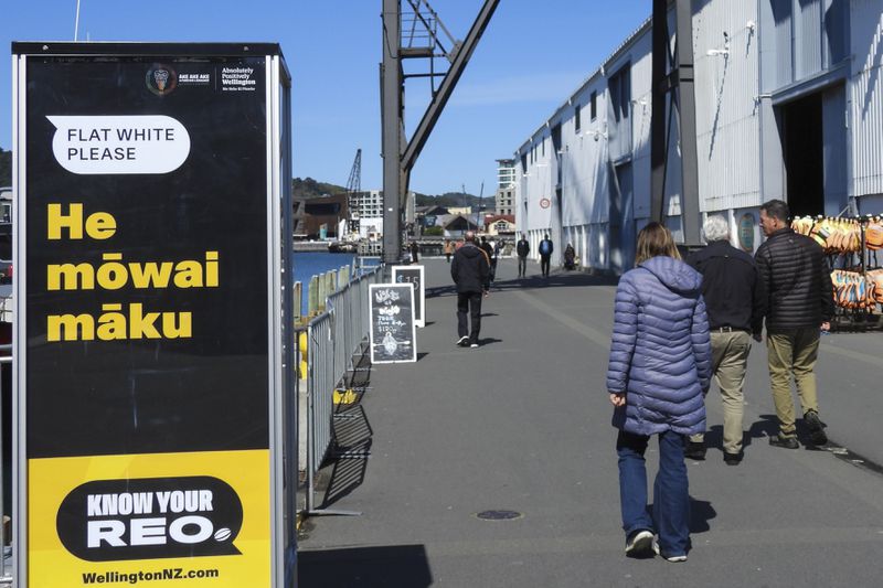 People walk past a sign encouraging them to order a coffee in Maori, during annual Maori language week in Wellington, New Zealand, Wednesday, Sept. 18, 2024. (AP Photo/Charlotte GrahamMcLay)