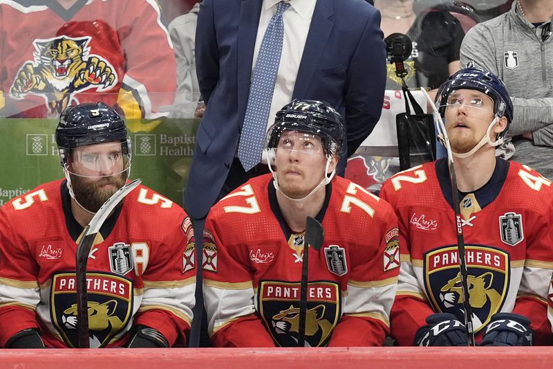Florida Panthers defensemen Aaron Ekblad (5), Niko Mikkola (77) and Gustav Forsling (42), sit on the bench during the third period of Game 5 of the NHL hockey Stanley Cup Finals against the Edmonton Oilers, Tuesday, June 18, 2024, in Sunrise, Fla. The Oilers defeated the Panthers 5-3. (AP Photo/Rebecca Blackwell)