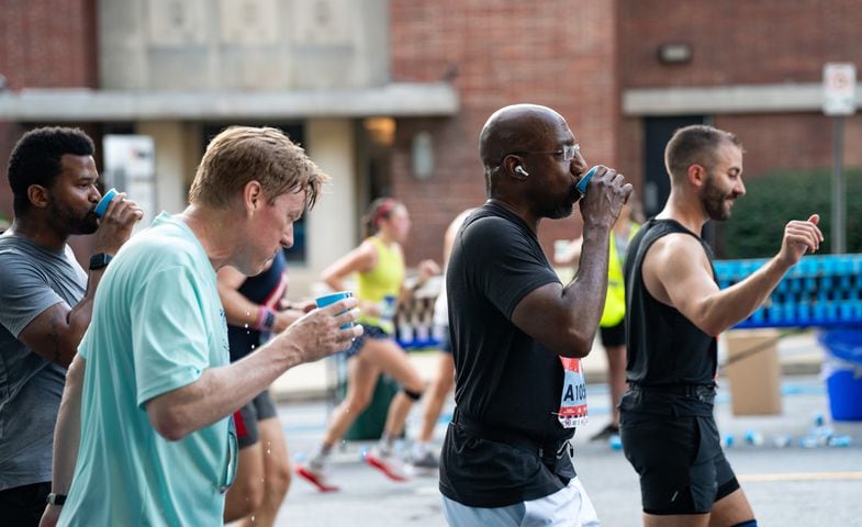 U.S. Sen. Raphael Warnock takes a drink of water during the 55th running of The Atlanta Journal-Constitution Peachtree Road Race at "Cardiac Hill" on Peachtree Road NW in Atlanta on Thursday, July 4, 2024. (Seeger Gray / AJC)