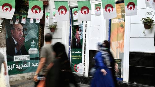 People walk past posters of Algerian President Abdelmadjid Tebboune, after the presidential elections results were announced and Tebboune being declared the winner of Algeria's election, Sunday, Sept. 8, 2024, in the capital Algiers. (AP Photo/Fateh Guidoum)