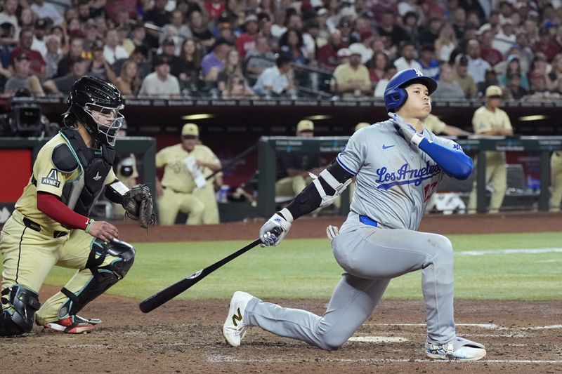 Los Angeles Dodgers designated hitter Shohei Ohtani, right, of Japan, strikes out as Arizona Diamondbacks catcher Jose Herrera, left, catches the pitch during the sixth inning of a baseball game Friday, Aug. 30, 2024, in Phoenix. (AP Photo/Ross D. Franklin)