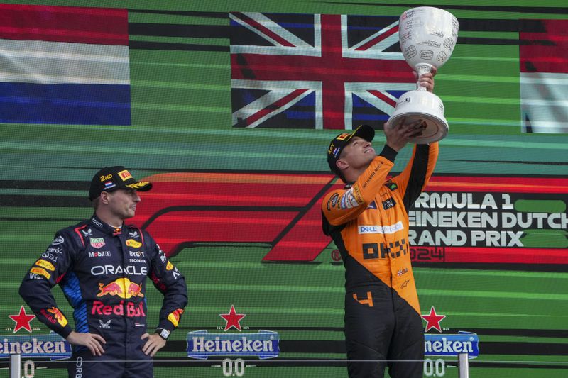 McLaren driver Lando Norris of Britain celebrates after winning the Formula One Dutch Grand Prix race, as Red Bull driver Max Verstappen of the Netherlands, left, looks on, at the Zandvoort racetrack, Netherlands, Sunday, Aug. 25, 2024. (AP Photo/Peter Dejong)