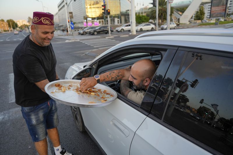 Israeli man Avi Azran distributes sweets to celebrate the news of the death of Hezbollah leader Hassan Nasrallah in the northern Israeli city of Nahariya, Saturday, Sept. 28, 2024. (AP Photo/Baz Ratner)