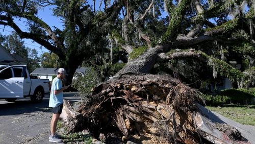 Nealy Hiers, student at Valdosta State University, takes a picture of a fallen tree caused by Hurricane Helene near Valdosta State University, Saturday, September 28, 2024, in Valdosta. The devastation in Valdosta was extensive after the South Georgia city was battered with hurricane-force winds on Helene’s path across the state. Damaging Helene has swept through Georgia, leading to at least 15 deaths. All 159 counties are now assessing the devastation and working to rebuild, even as serious flooding risks linger. (Hyosub Shin / AJC)