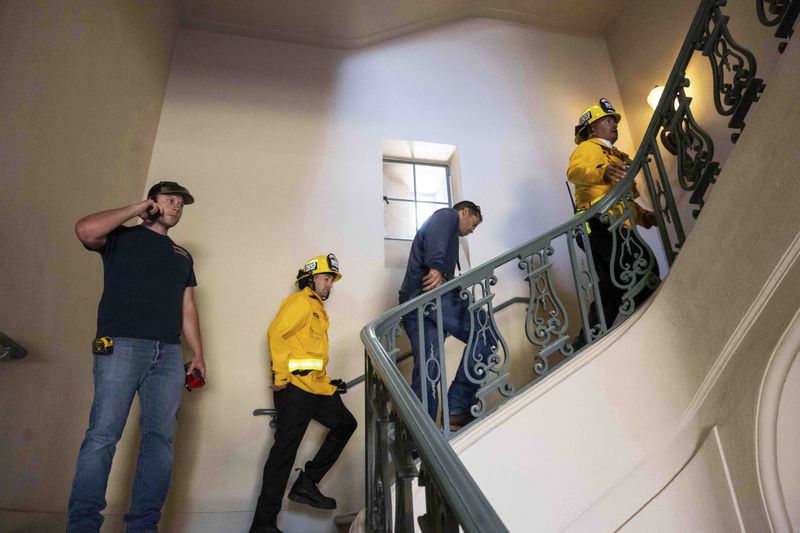 Pasadena Fire Inspectors Mitchell Phillips and Roman Castillo lead people up the stairs of Pasadena City Hall on Monday, Aug. 12, 2024, in Pasadena, Calif., after an earthquake was strongly felt from the Los Angeles area all the way to San Diego. (Sarah Reingewirtz/The Orange County Register via AP)