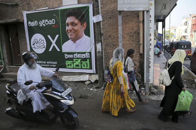 A motorist drives past an election campaign poster featuring a photograph of presidential candidate Sajith Premadasa and in Sinhalese reads, 'forward together-winning president Sajith' in a muslim neighborhood of Colombo, Sri Lanka, Wednesday, Nov. 13, 2019. (AP Photo/Eranga Jayawardena, File)