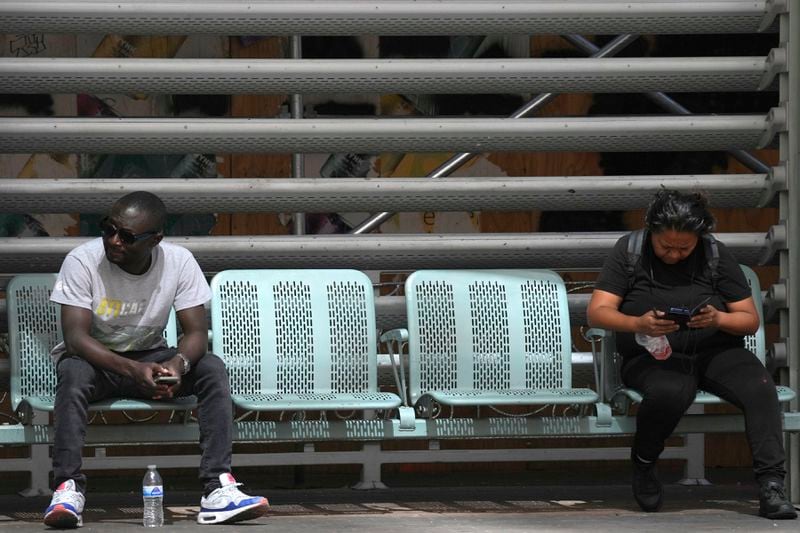People sit at a light rail stop as the temperature hits 104-degrees Monday, June 17, 2024, in Phoenix. (AP Photo/Ross D. Franklin)