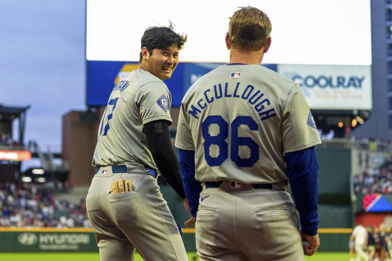 Los Angeles Dodgers two-way player Shohei Ohtani, left, shares a laugh with first base coach Clayton McCullough, right, before he takes the field after the National Anthem in the xxxx inning of a baseball game against the Atlanta Braves, Saturday, Sept. 14, 2024, in Atlanta. (AP Photo/Jason Allen)