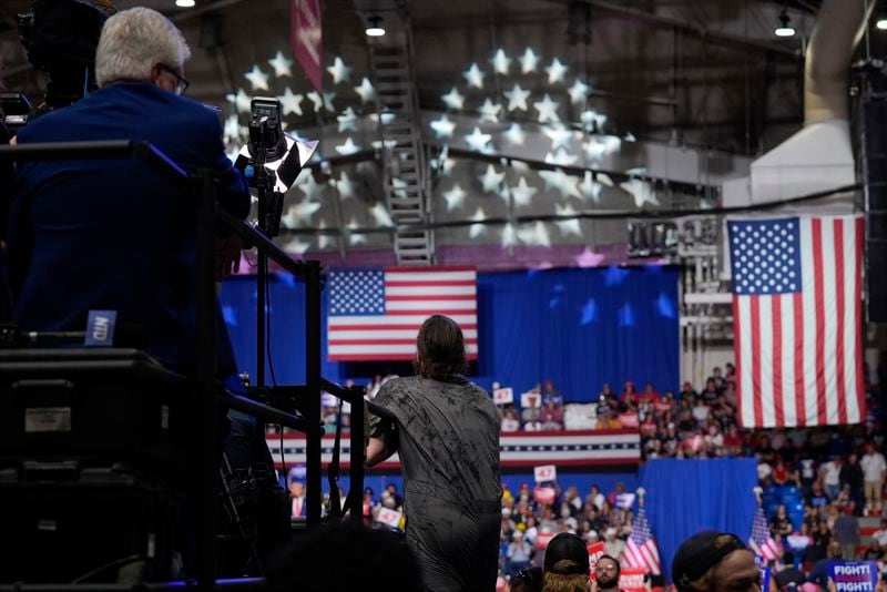 A man, center, climbs onto the media riser, before police removed him, as Republican presidential nominee former President Donald Trump speaks at a campaign event, Friday, Aug. 30, 2024, in Johnstown, Pa. (AP Photo/Alex Brandon)