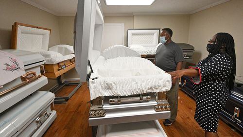 Carol Plummer Wright helps a client in the casket show room at Dudley Funeral Home in Dublin in March. The funeral home handled a high number of funerals over the last year. Now some of those families may be eligible for federal relief. (Hyosub Shin / Hyosub.Shin@ajc.com)