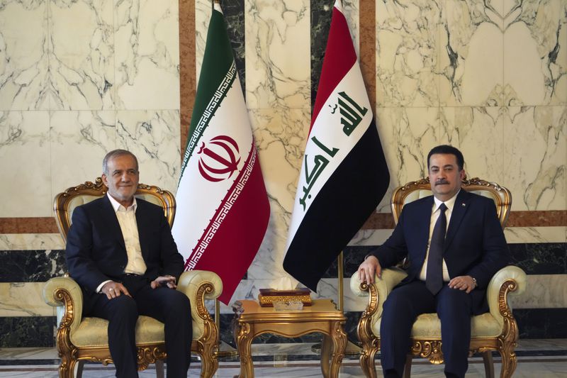 Iranian President Masoud Pezeshkian, left, is welcomed by Iraqi Prime Minister Mohammed Shia al-Sudani, right, in Baghdad, Iraq, Wednesday Sept. 11, 2024. (Murtadha Al-Sudani/Pool Photo via AP)