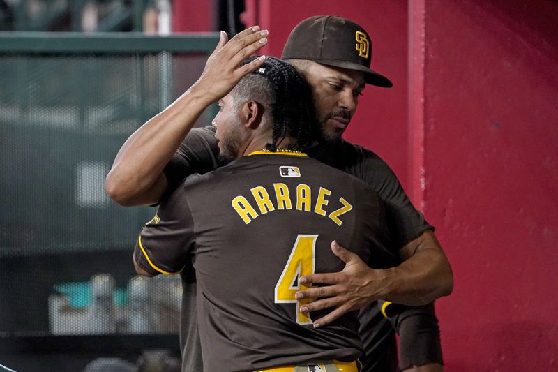 San Diego Padres' Luis Arraez (4) gets a hug in the dugout from teammate Xander Bogaerts, right, after hitting a double against the Arizona Diamondbacks during the sixth inning of a baseball game, Sunday, Sept. 29, 2024, in Phoenix. (AP Photo/Darryl Webb)