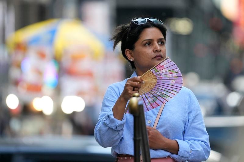 A woman fans herself in Bryant Park, Thursday, June 20, 2024, in New York. (AP Photo/Pamela Smith)