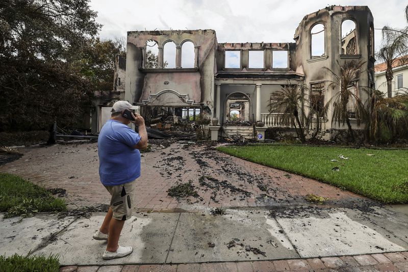 Joe Daum looks at the remains of a friend's home that burned during Hurricane Helene on Davis Island Saturday, Sept. 28, 2024, in Tampa, Fla. (AP Photo/Mike Carlson)